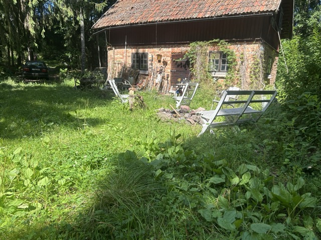 Tegelladan omgiven av frodig sommargröska – hjärtat i gården